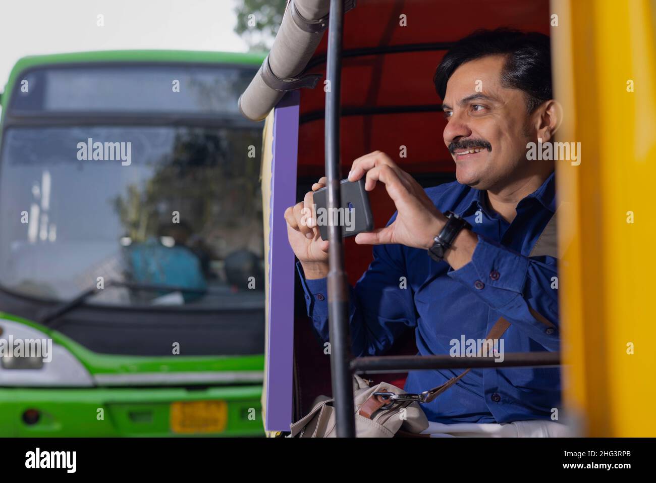 Man capturing photo in Smartphone while going to office by Auto Rickshaw Stock Photo
