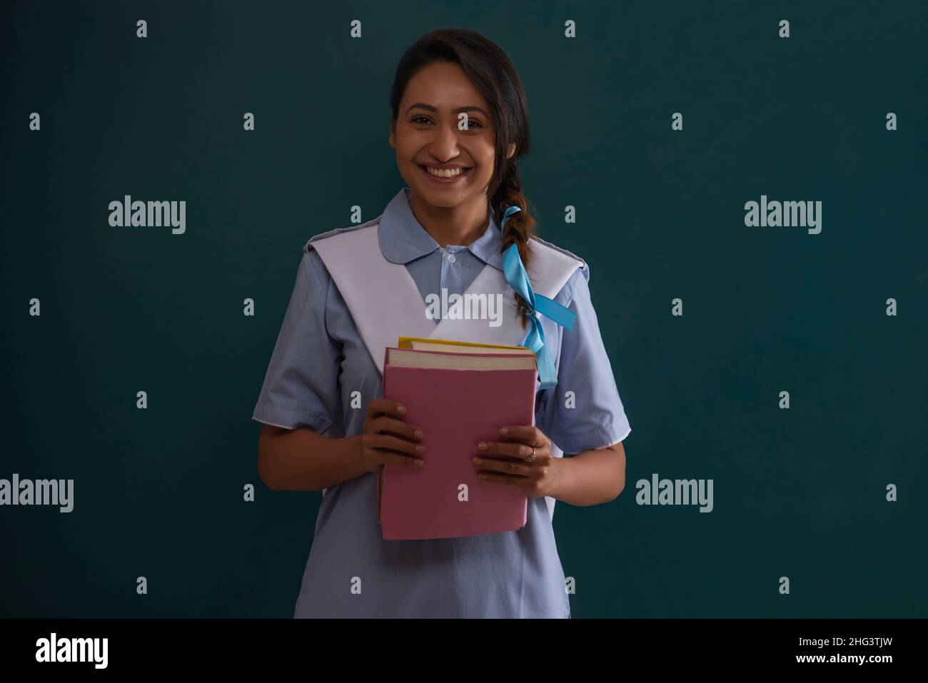 Young girl in school uniform standing with holding books Stock Photo