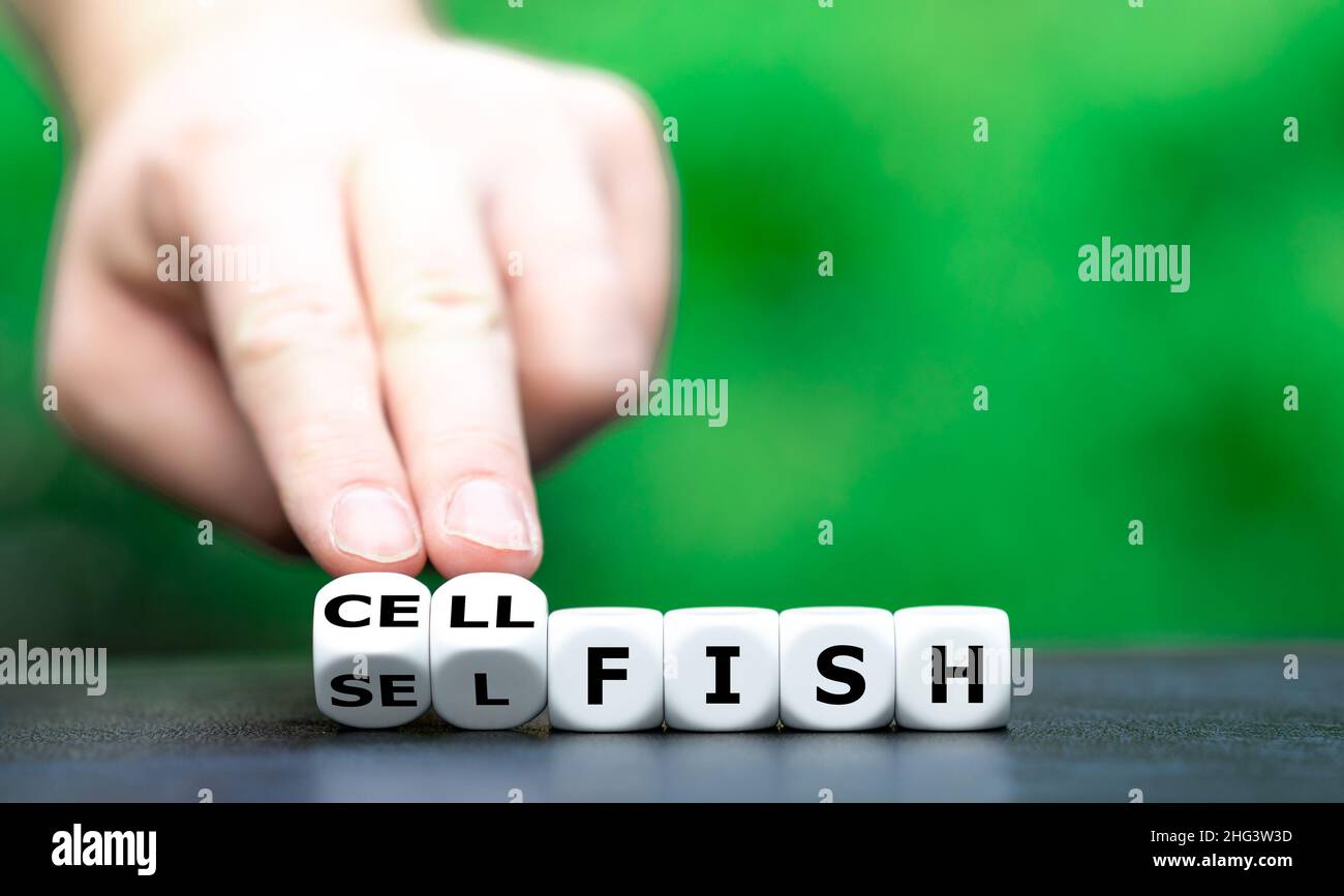 Symbol for a selfish person who is talking a lot on a cell phone. Hand turns dice and changes the word 'selfish' to 'cellfish'. Stock Photo