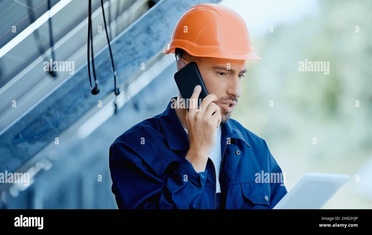 engineer talking on smartphone while holding digital tablet Stock Photo