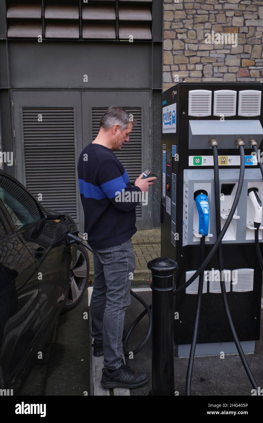 Driver pays to charge his car at an EV charging point in bristol England Stock Photo