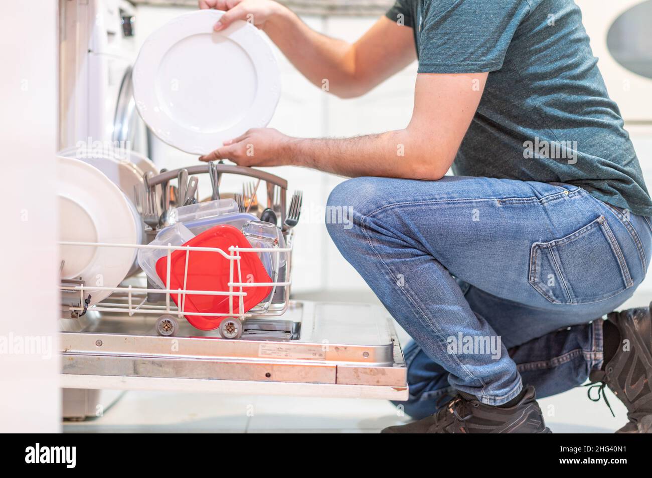 Unrecognizable adult male setting the dishwasher. Man doing housework. Concept of feminist equality Stock Photo