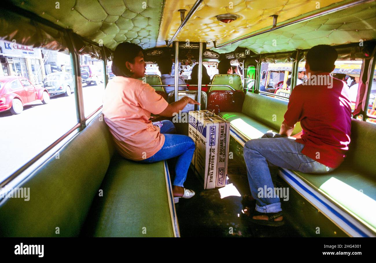 Passengers aboard a jeepney van in Metro Manila on Luzon Island in the Philippines. Jeepneys are the most popular means of public transportation among Filipino locals. The eye-catching vans are known for their crowded seating and flamboyant exterior decorations, making them one of the more quirky aspects of art and culture in the Philippines. Stock Photo
