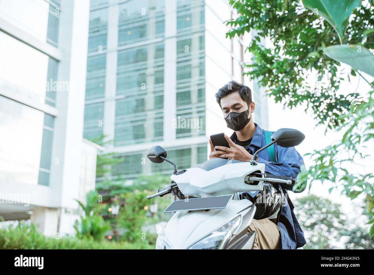 Asian man with mask using a cellphone on a motorcycle Stock Photo Alamy