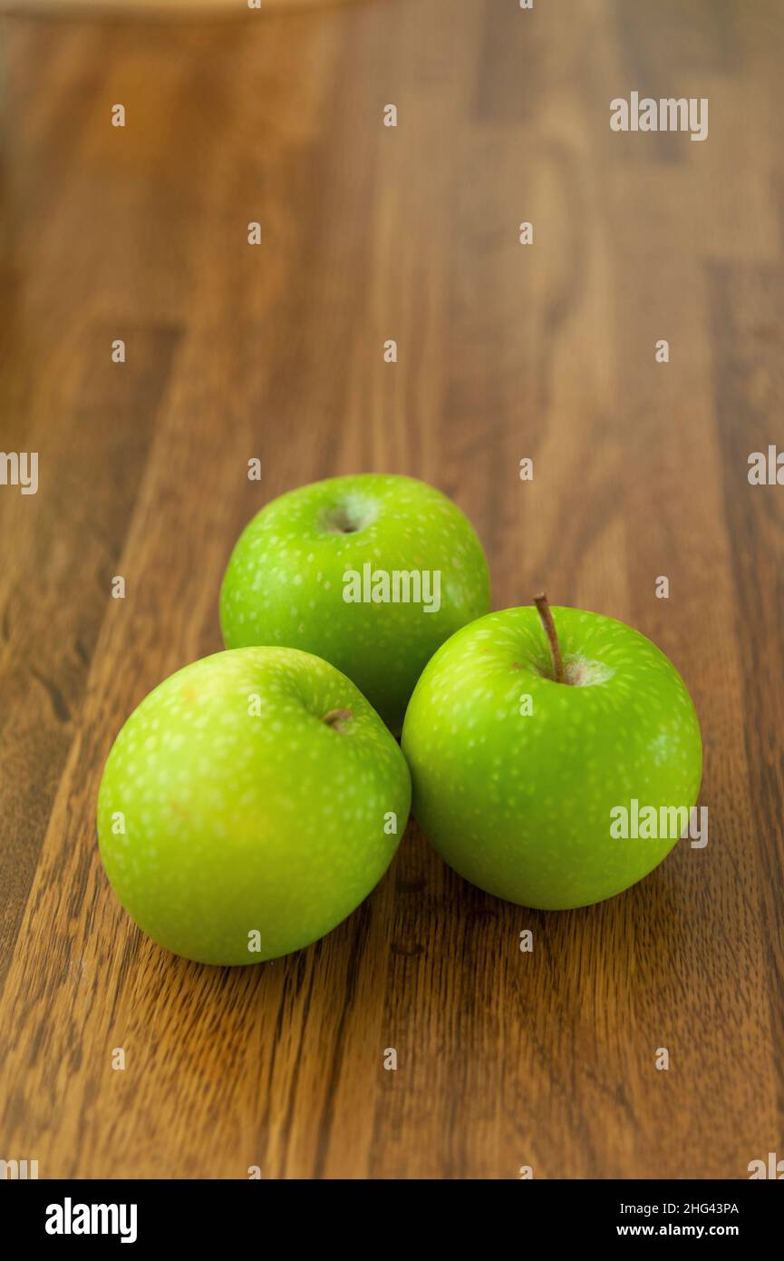 Speckled Granny Smiths apples on wood effect worktop Stock Photo