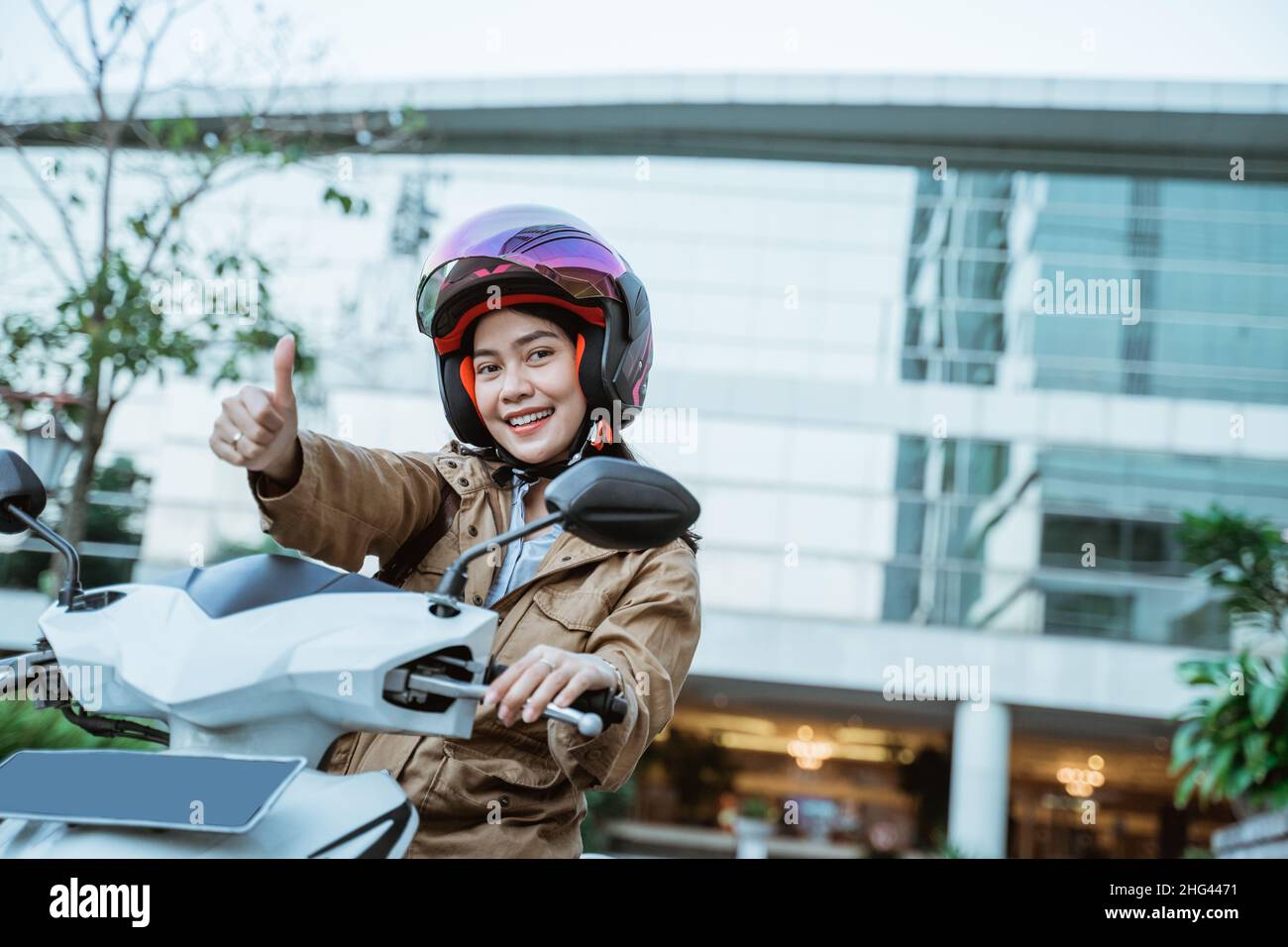 Woman wearing helmet while riding motorbike with thumbs up Stock Photo