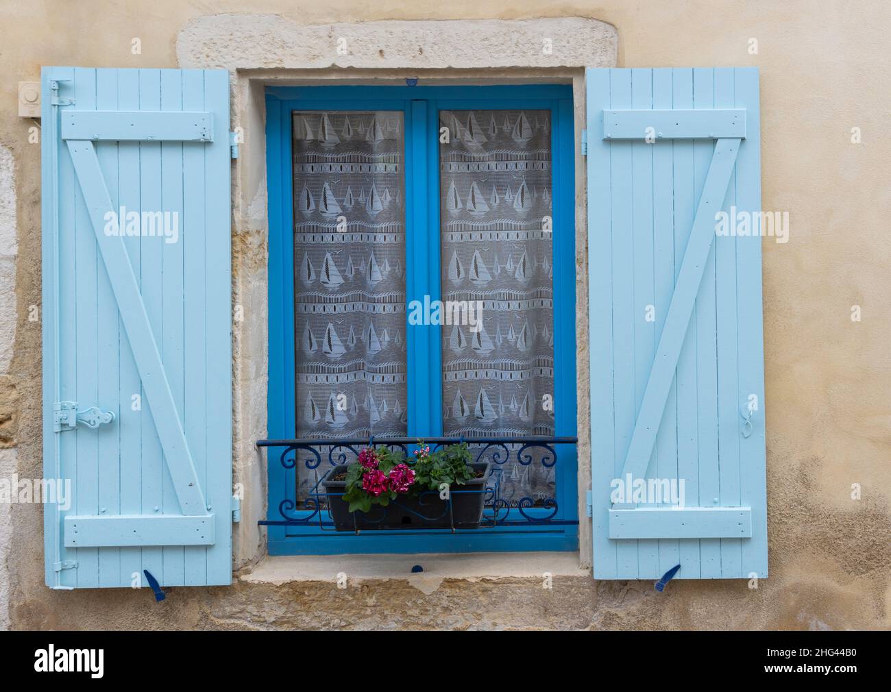Blue wooden window shutters with some flowers, France. Stock Photo