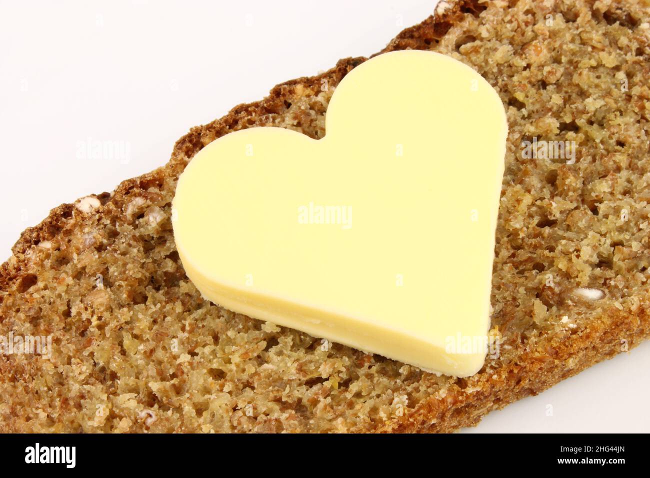 A slice of whole wheat bread with heart shaped butter. Stock Photo