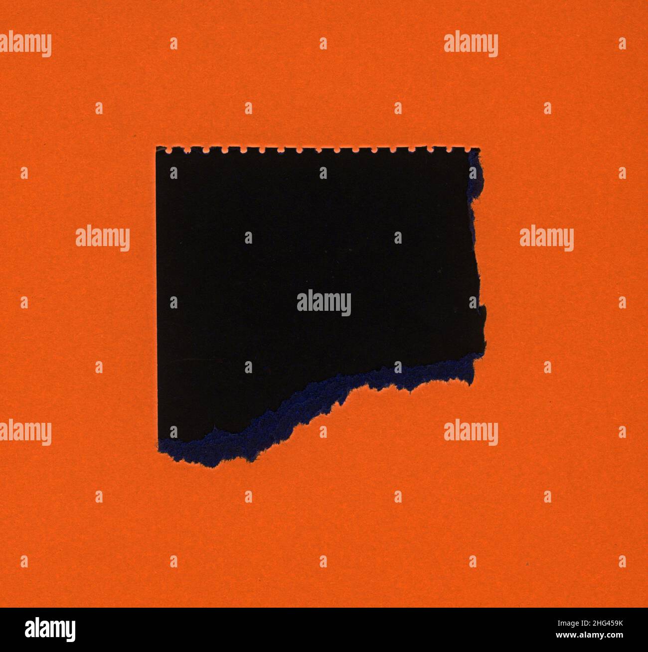 torn orange paper with black hole copy space Stock Photo