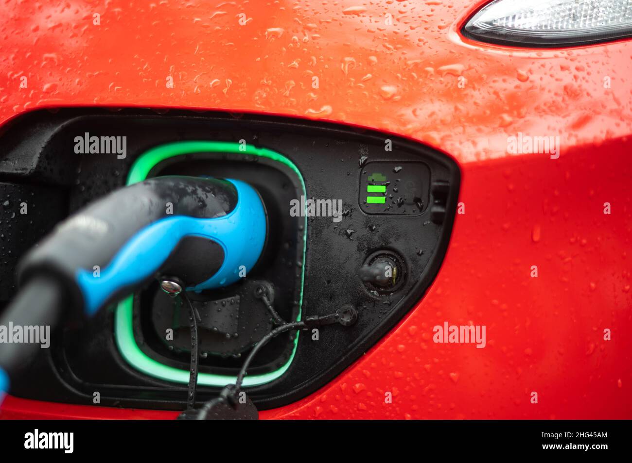 charging red electric car on a rainy day Stock Photo Alamy