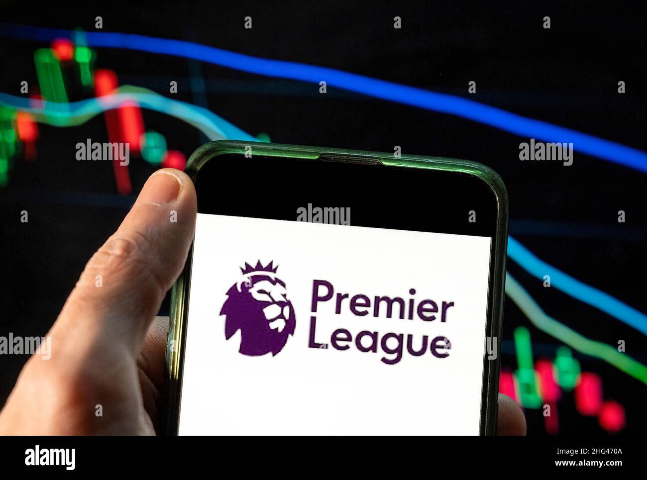 In this photo illustration the English football league Premier League logo seen displayed on a smartphone with an economic stock exchange index graph in the background. Stock Photo