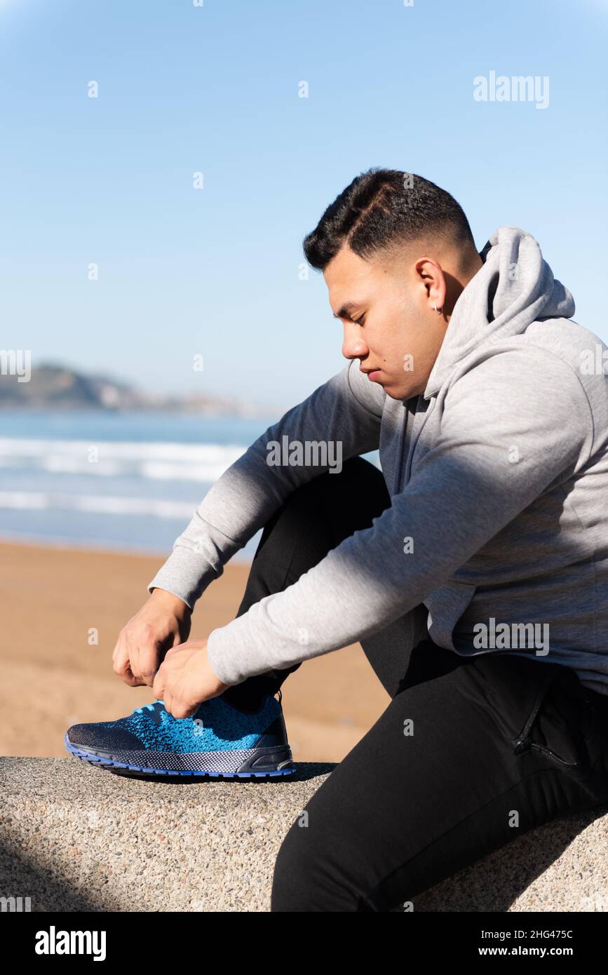 Young latin man tying laces before training. Focus and determination on sports concept. Stock Photo