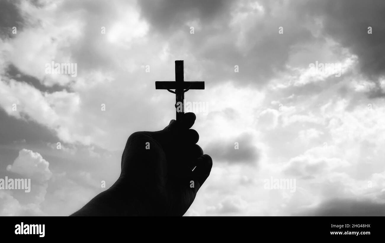 hand holding holy Cross with bright sky background. Christianity concept. Stock Photo