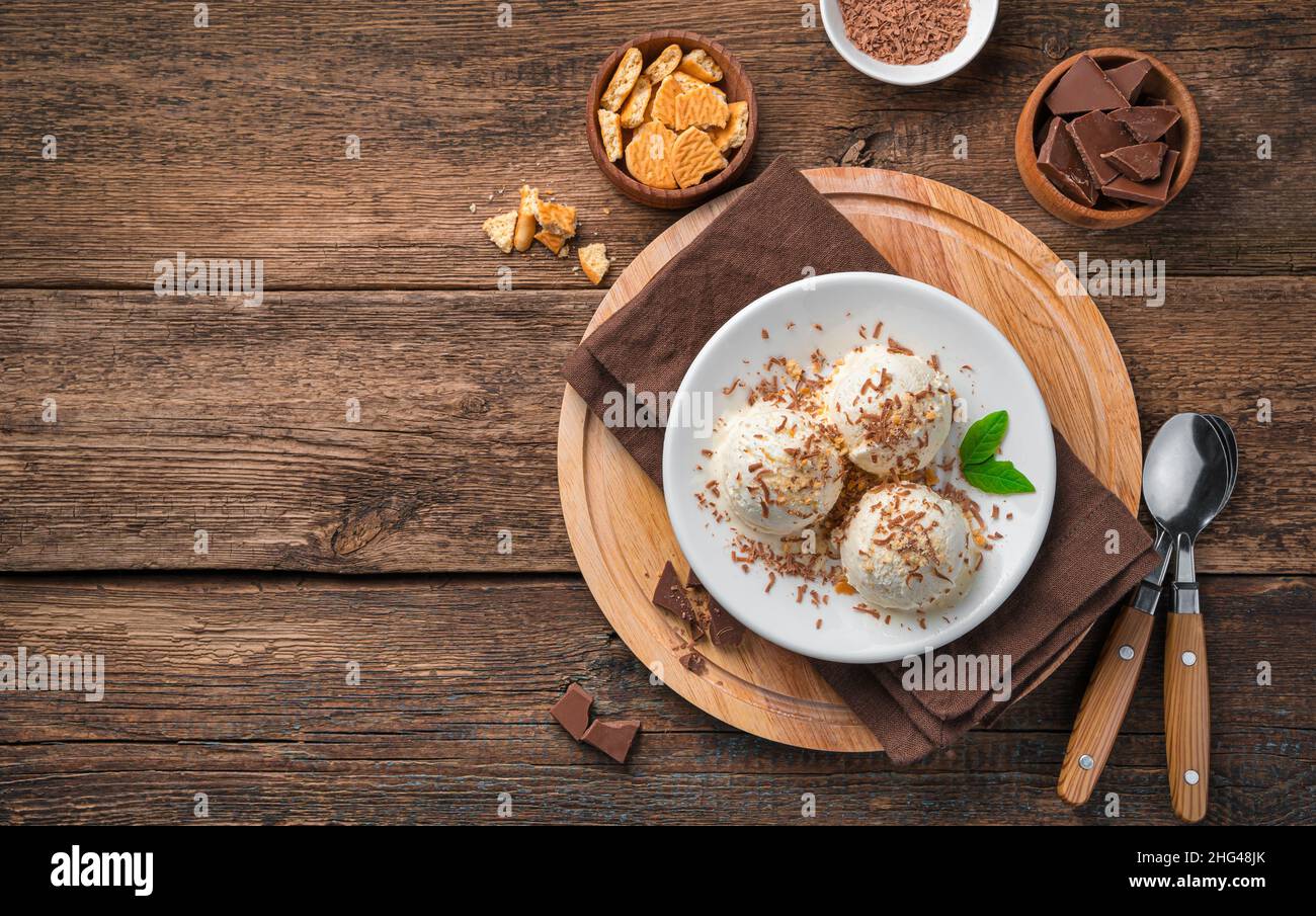 Three balls of creamy ice cream with chocolate chips on a wooden background. Top view, copy space. Stock Photo