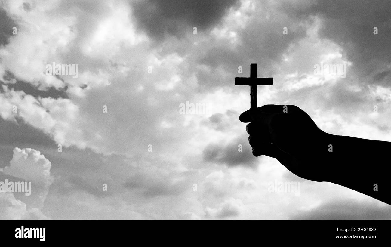 hand holding holy Cross with bright sky background. Christianity concept. Stock Photo