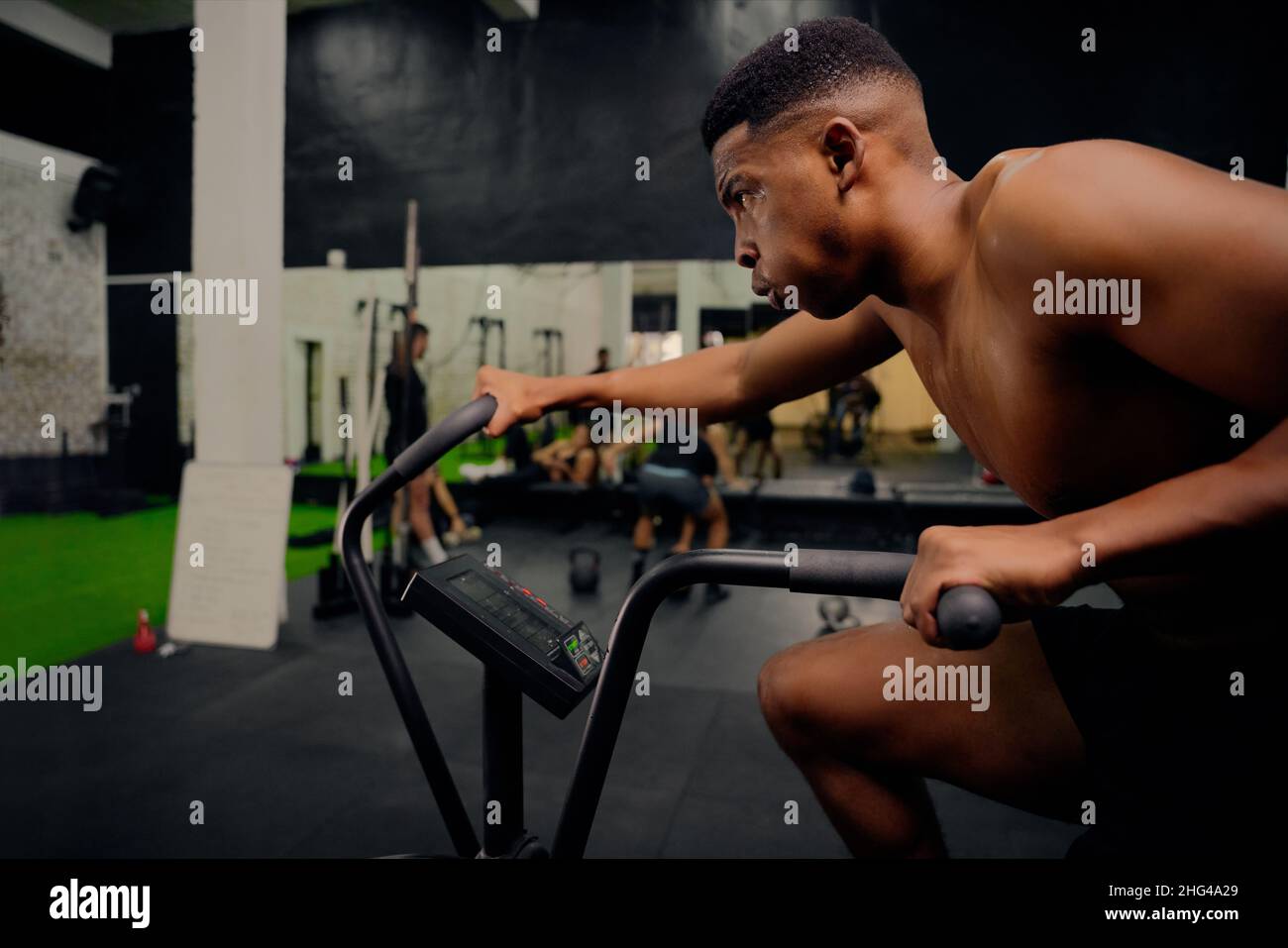 African American male using an elliptical trainer during cross training. Male athlete exercising intensely in the gym. High quality photo Stock Photo
