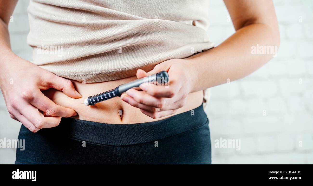 A woman injects insulin with insulin injection device into the
