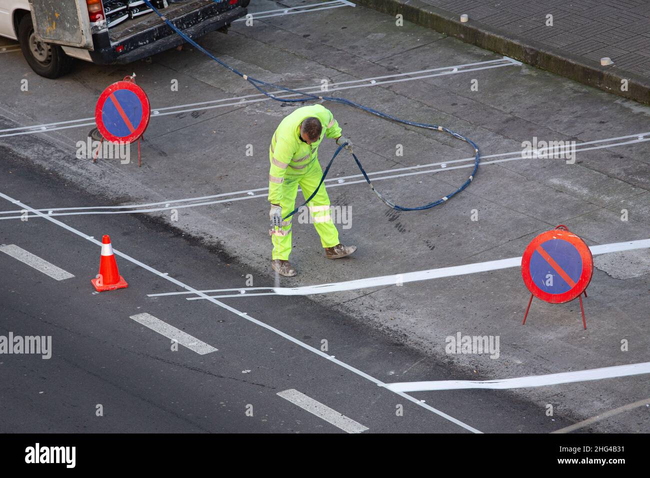 Galicia, Spain; january 18, 2022: Road painter painting lines on asphalt using a paint sprayer gun Stock Photo