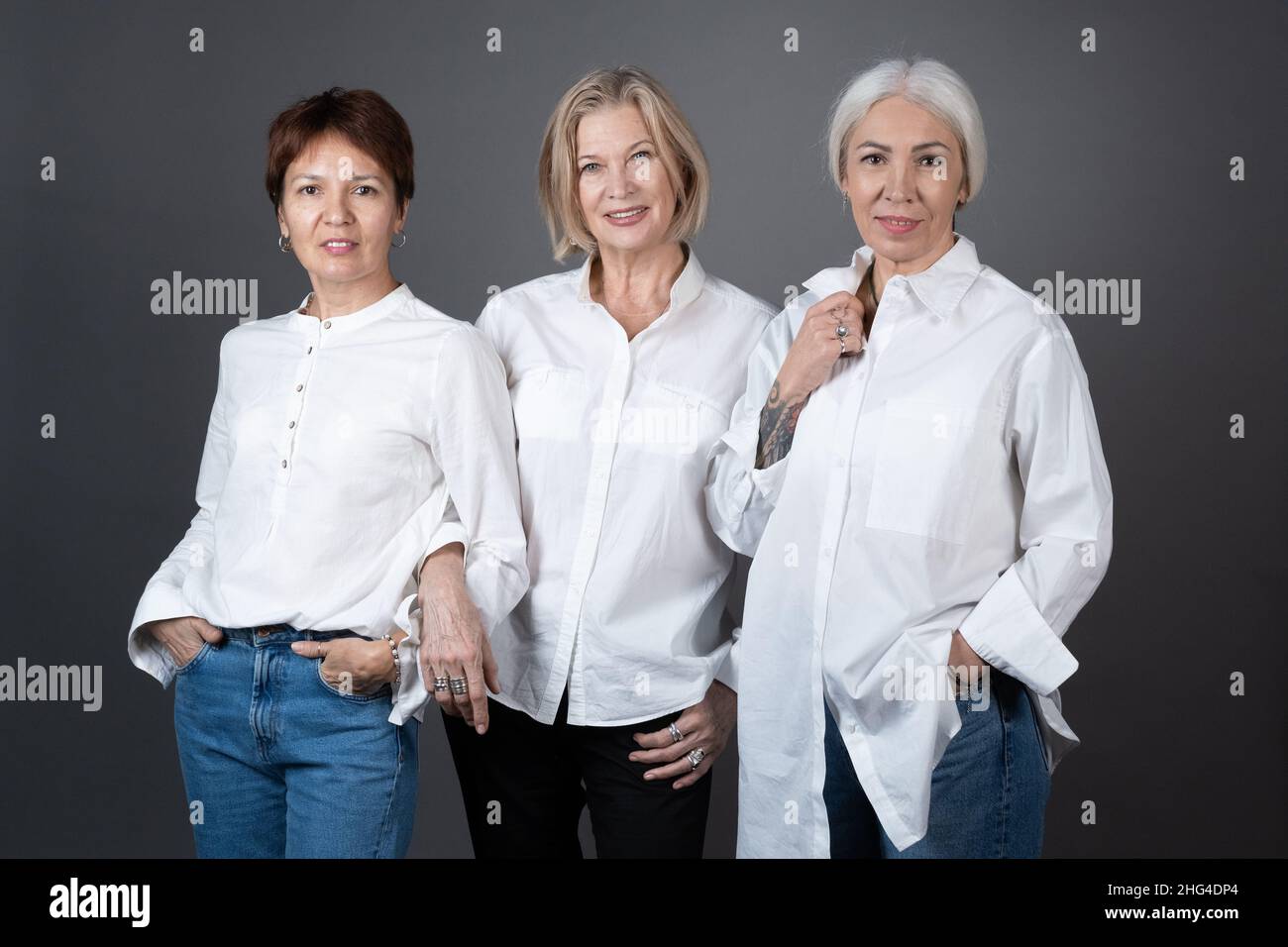 Portrait of stylish mature women posing at camera together against the grey background Stock Photo