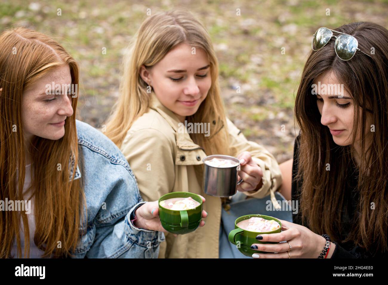 Three young beautiful women drink hot cocoa with marshmallows Stock Photo