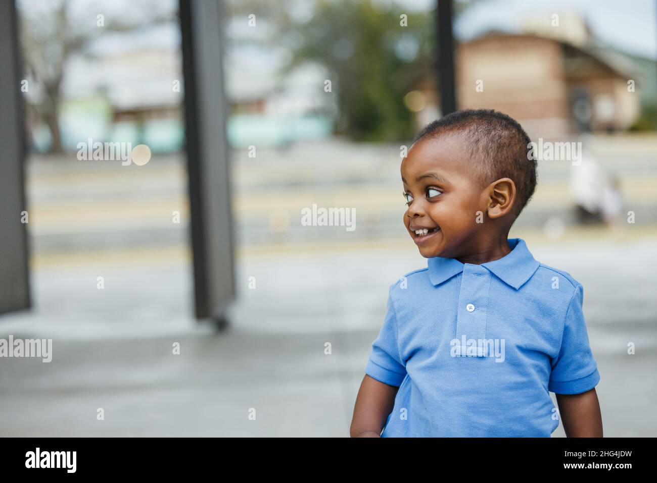 A cute one year old toddler almost preschool age African-American boy with big eyes smiling and looking away with copy space Stock Photo