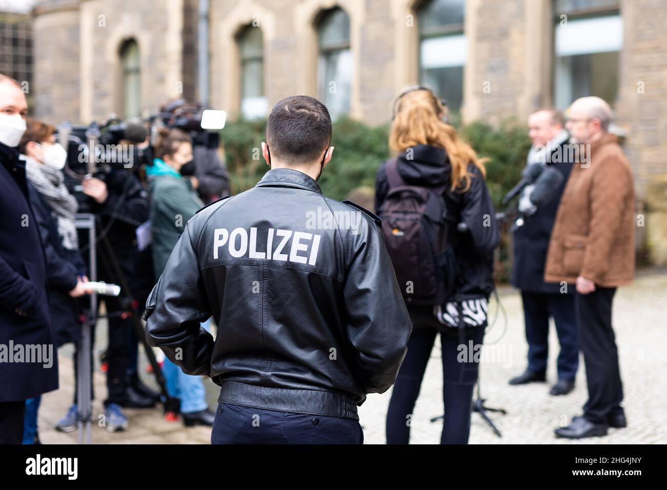 Hanover, Germany. 18th Jan, 2022. A police press officer stands next to journalists during a press statement by Boris Pistorius (2nd from right, SPD), Interior Minister of Lower Saxony, and Volker Kluwe (r), Chief of Police of the Hanover Police Directorate. Investigators have stopped a major cybercrime network. Fifteen servers were taken down in ten countries, Europol announced. The action was under the leadership of the Hanover Police Directorate. Credit: Moritz Frankenberg/dpa/Alamy Live News Stock Photo