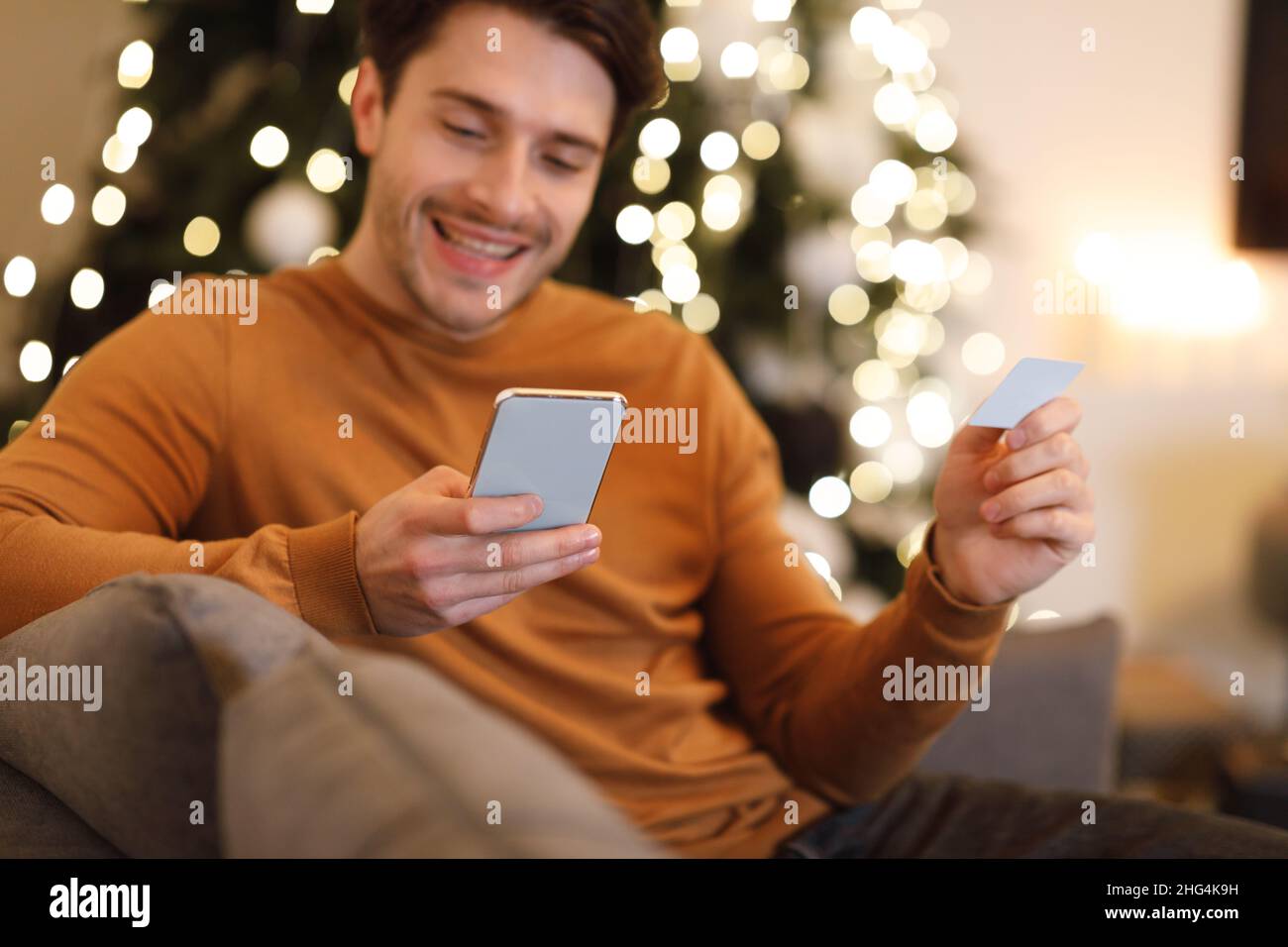 Happy man holding debit credit card, using cellphone Stock Photo