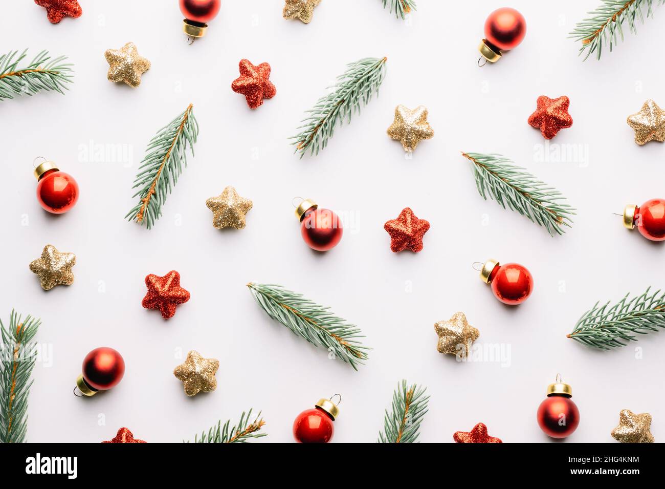 Creative Christmas background with Christmas balls, pine twigs, red and golden stars decorations on white background. Flat lay, top view, copy space Stock Photo