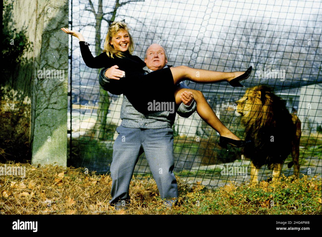 Comedian Roy Kinnear with page three model Suzanne Mizzi at London Zoo in Regents Park, watched by caged feline Dax. Stock Photo