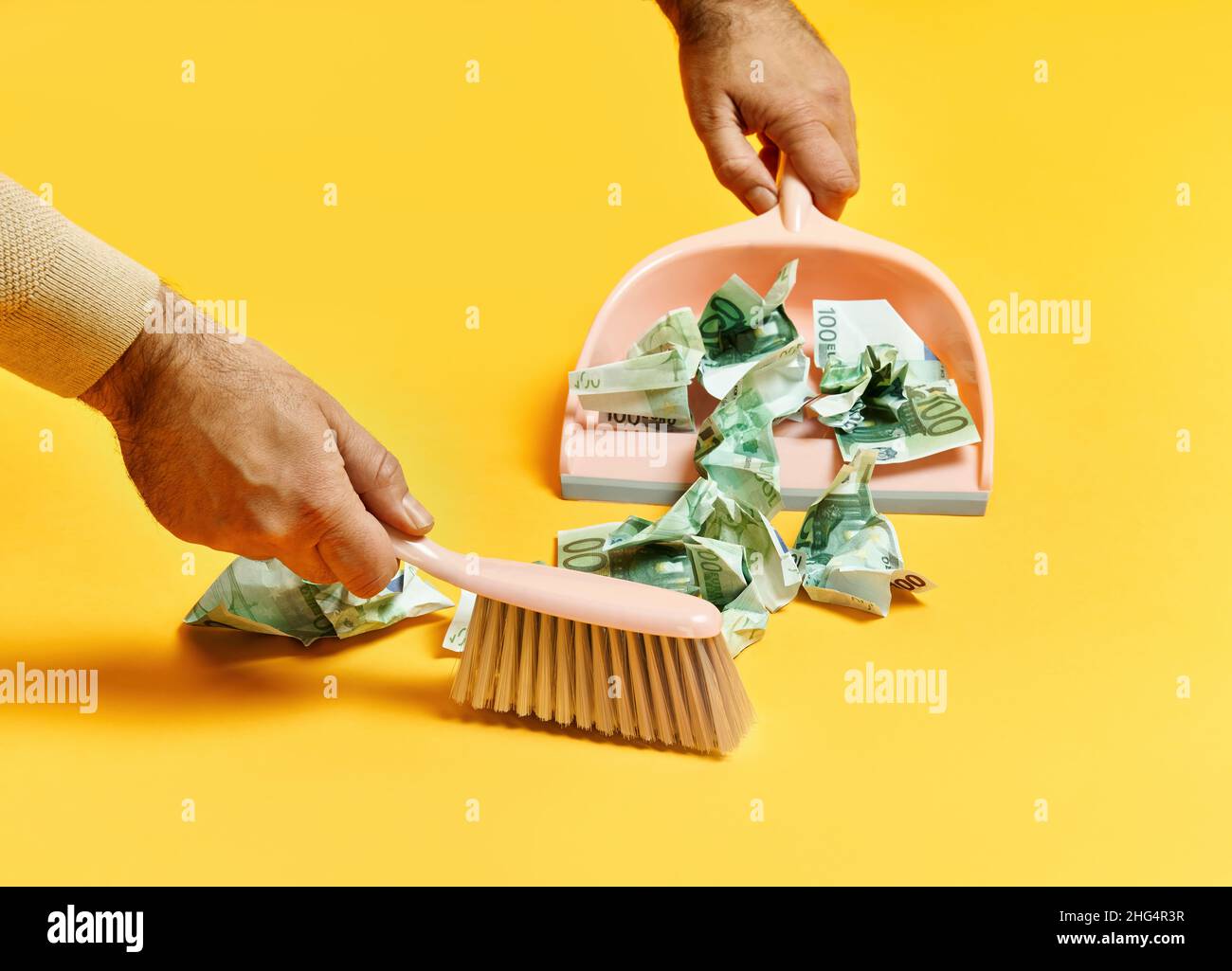 Creative layout with male hand sweeping money dollar bills on yellow
