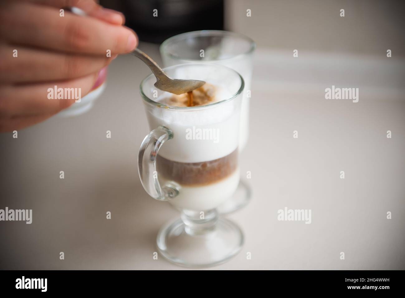 The hands of a young man make coffee from a coffee machine. Morning latte for breakfast at home. Homemade barista cappuccino in a stylish kitchen. Clo Stock Photo