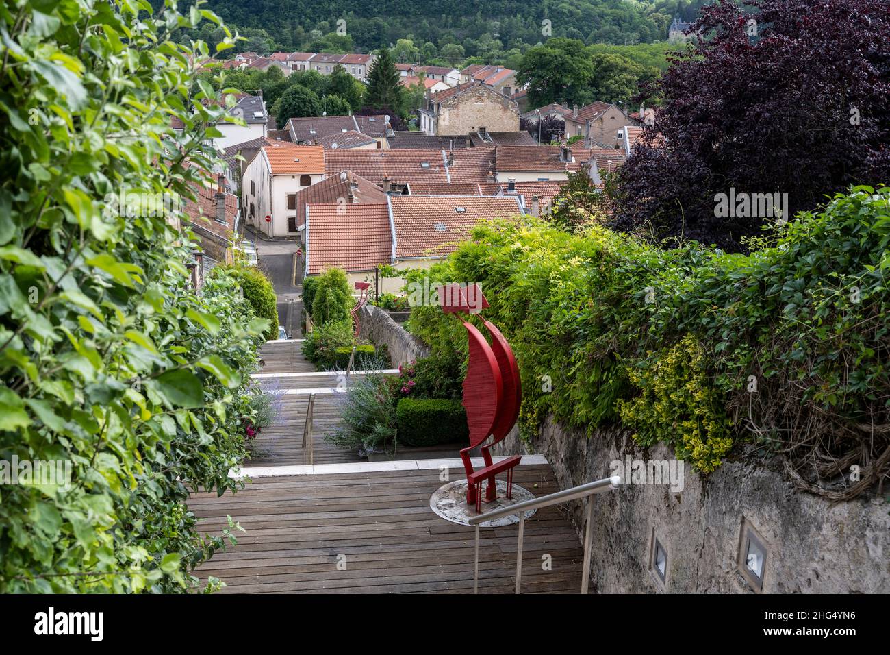 Liverdun, France - June 27, 2020: Street with stairs in Liverdun in France with old houses, forest and art on the stairs. Stock Photo