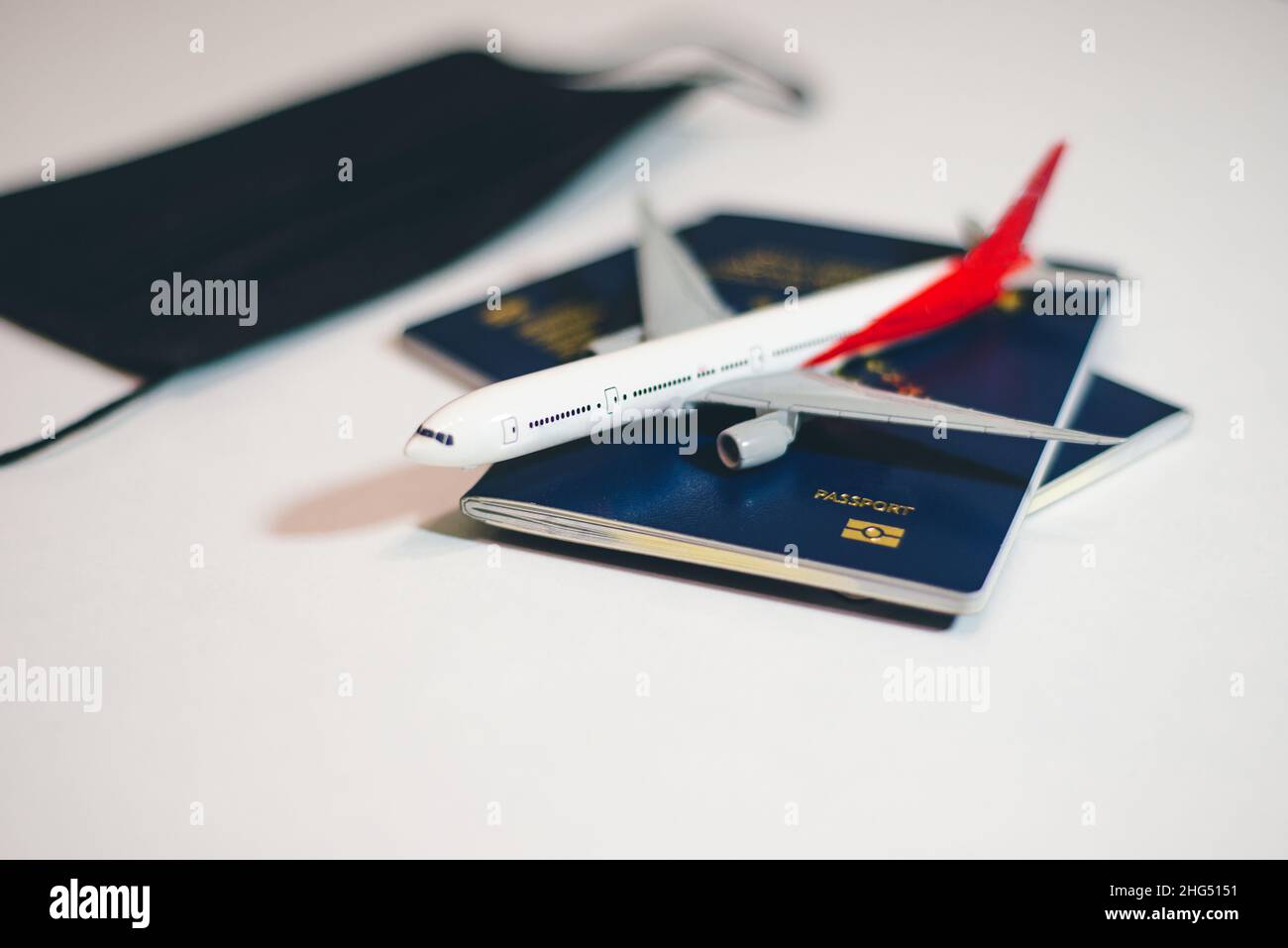 Airplane with passports and face mask on the table , covid 19 flight restrictions Stock Photo