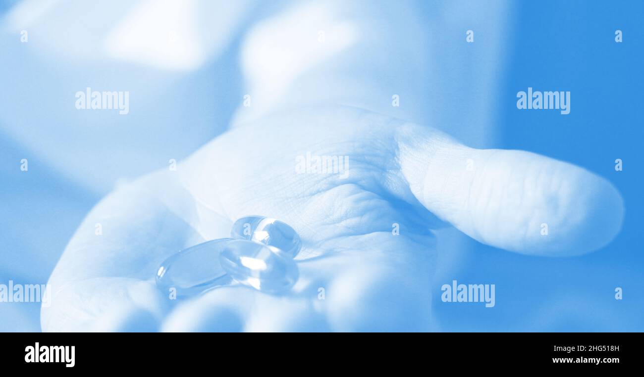 Soft gels pills with Omega-3 oil spilling out of pill bottle close-up iin aged woman hand. Healthcare concept . Selective foocus. Stock Photo