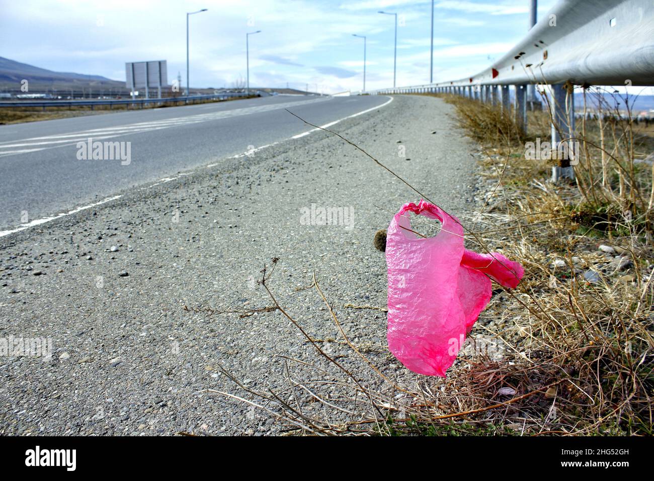 Pink polyethylene pash thrown away on the highway. Stock Photo