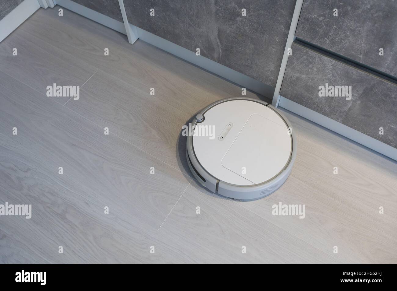 Smart House. Vacuum cleaner robot runs on wood floor in a living room ...