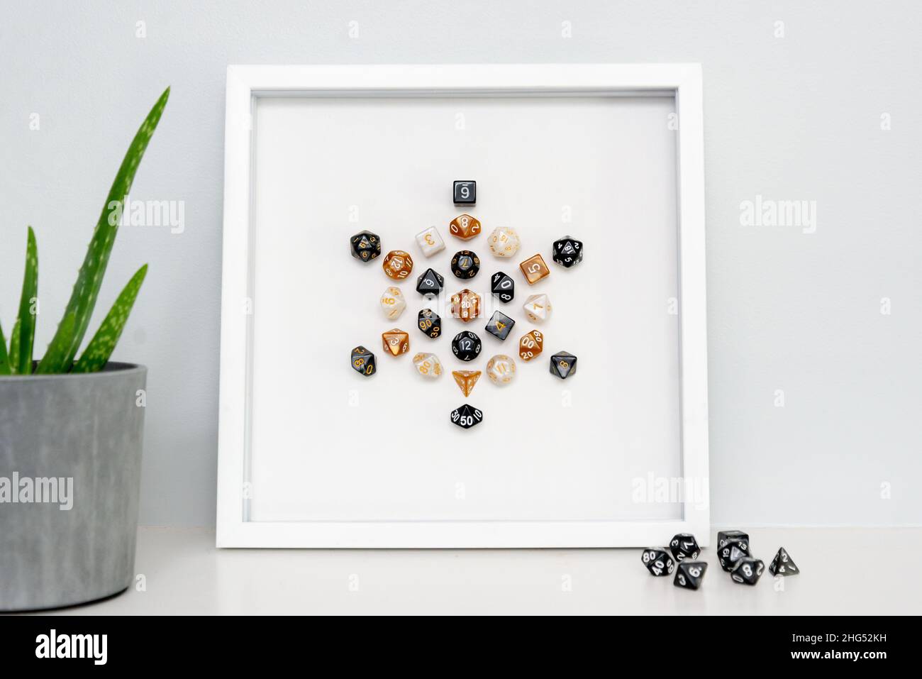 A framed piece of minimalist mixed-media art: a dice mandala created with colorful polyhedral dice used for role playing games like D&D. Stock Photo