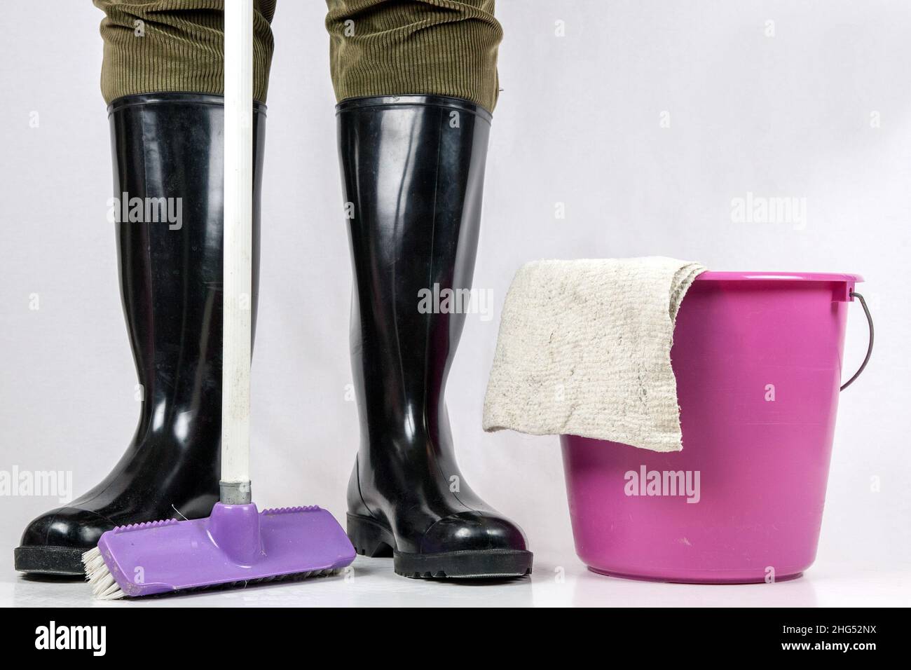 Man in rubber boots with scrubbing brush, mop bucket and cleaning cloth, things for thorough cleaning. Stock Photo