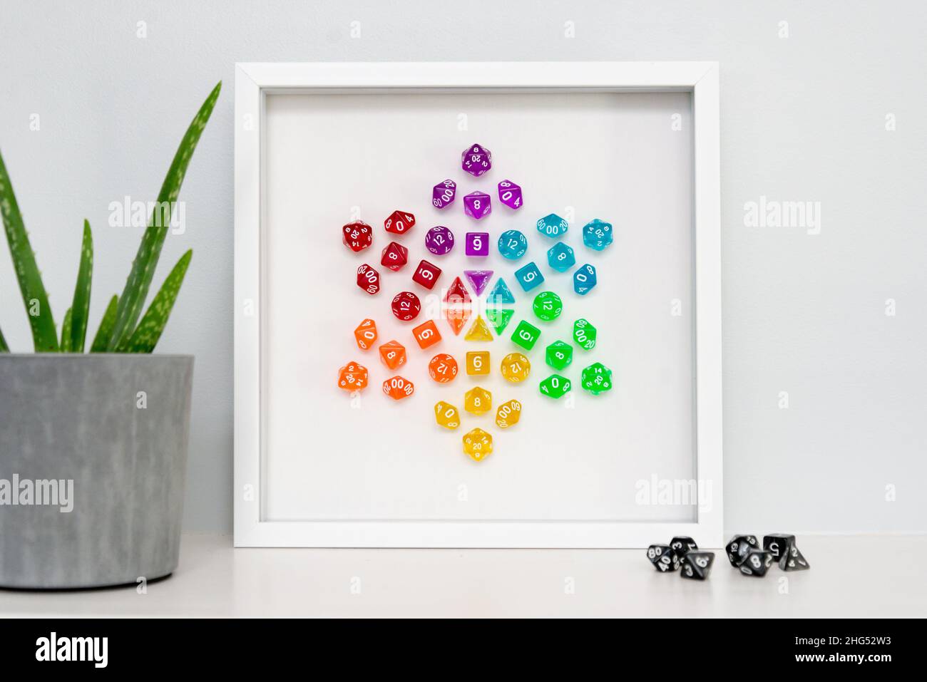 A framed piece of mixed media art: a mandala created with rainbow polyhedral dice used for role playing games like Dungeorns & Dragons. Stock Photo