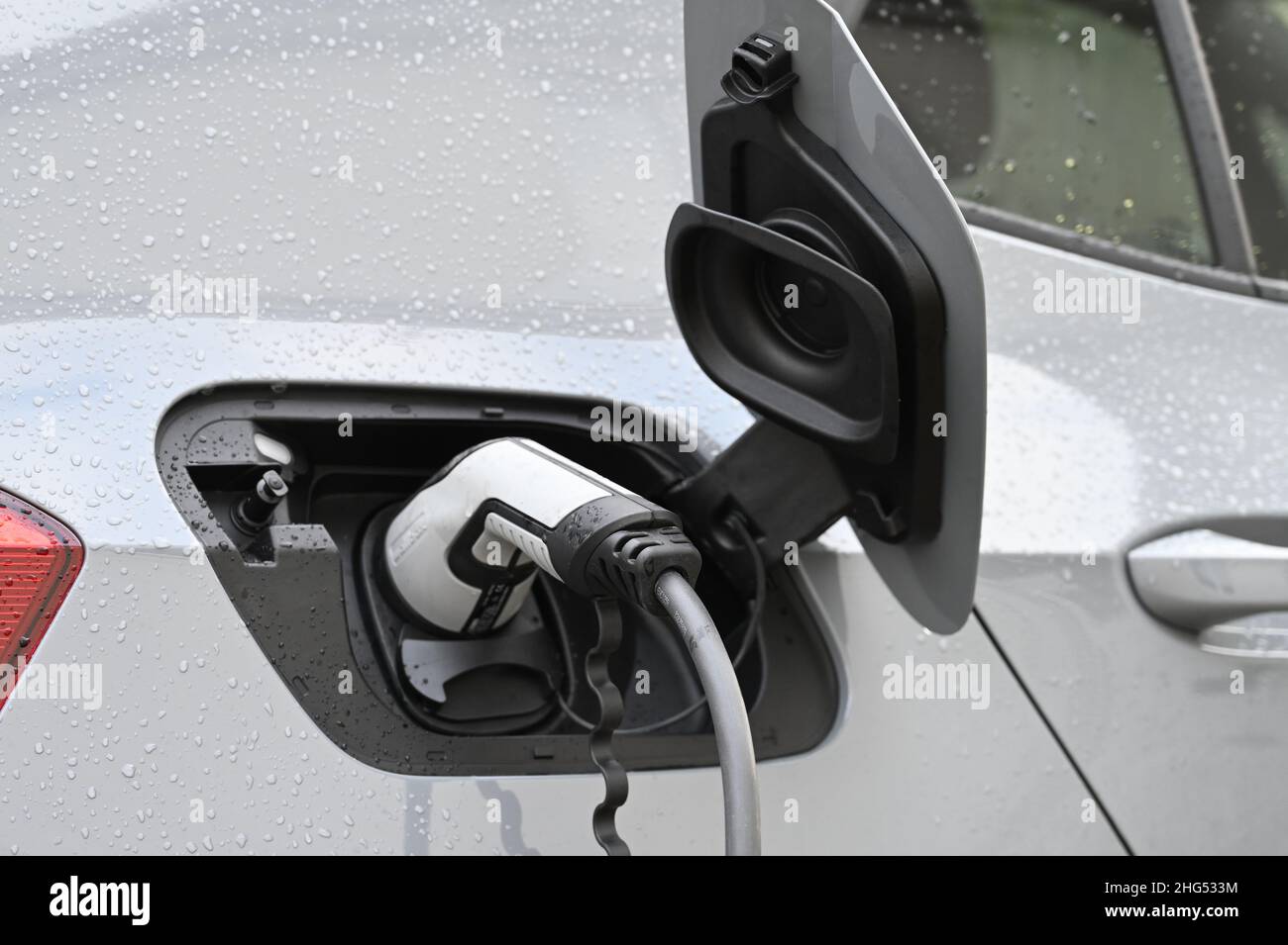 An electric car charging with its fuel flap open, in progress of charging the vehicle. Stock Photo