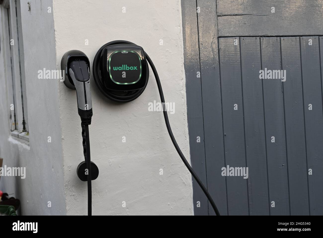 EV Electric charging box in its docking station positioned on the front on a wall of garage in a rural village in Nottinghamshire Stock Photo