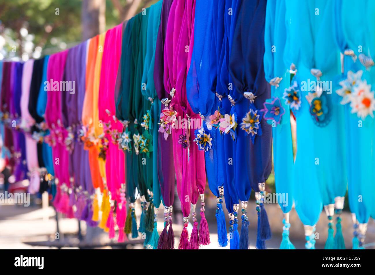 Colorful handmade or needle lace silk scarves lined up on a rope hanger in woman producer bazaar in Odemis, Izmir. Beautiful modern style chiffons. Stock Photo