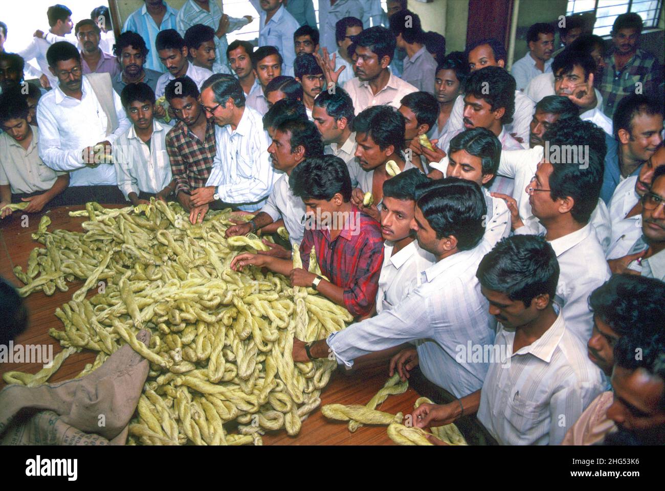 Businessmen inspecting and haggling over skeins of raw silk, or silk ropes, at a market in Bangalore. Karnataka, India Stock Photo