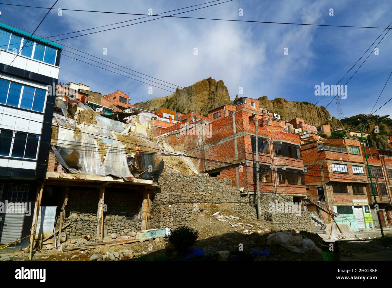 La Paz, Bolivia: Municipal workers stabilising a hillside and damaged houses with cages filled with rocks / gabions at a site in Tembladerani / Cotahuma district. Unauthorised excavation and earth moving by one of the property owners caused part of the hillside to collapse. Many of La Paz's hillside neighbourhoods have been built in unstable areas without proper permits or building controls. Subsidence and erosion causing landslides and houses to collapse are common, especially in the rainy season. In this incident 2 houses had to be demolished and 6 others were badly affected. Stock Photo