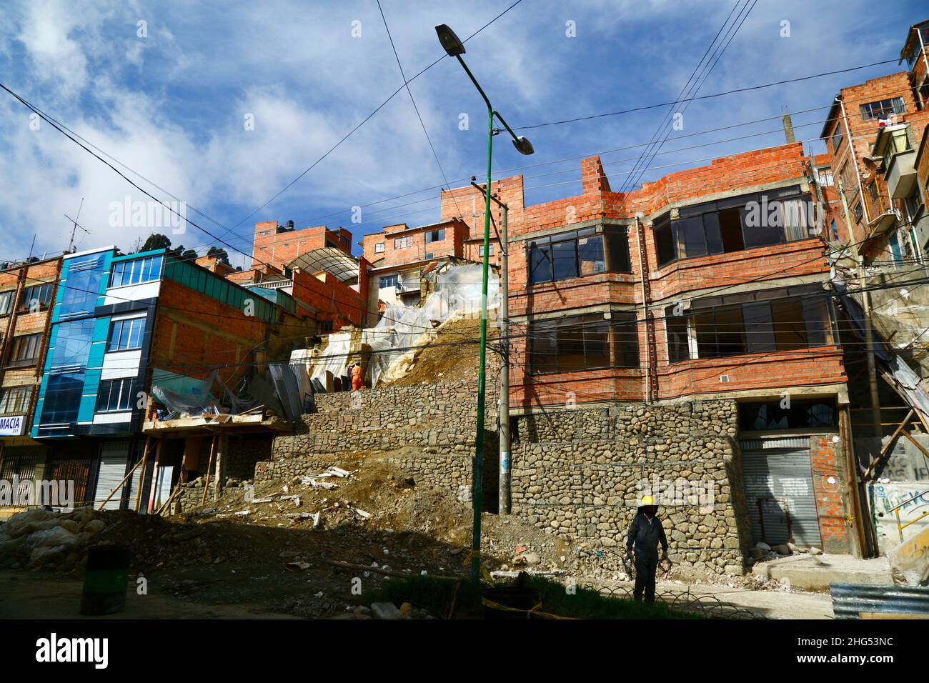 La Paz, Bolivia: Municipal workers stabilising a hillside and damaged houses with cages filled with rocks / gabions at a site in Tembladerani / Cotahuma district. Unauthorised excavation and earth moving by one of the property owners caused part of the hillside to collapse. Many of La Paz's hillside neighbourhoods have been built in unstable areas without proper permits or building controls. Subsidence and erosion causing landslides and houses to collapse are common, especially in the rainy season. In this incident 2 houses had to be demolished and 6 others were badly affected. Stock Photo