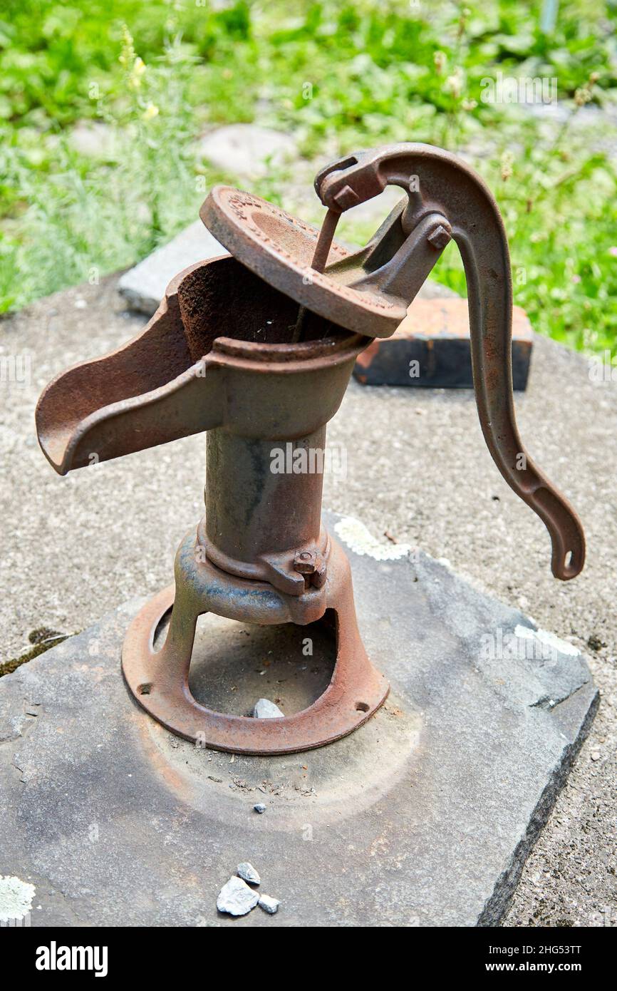 Rusty Manual Water Pump on Stone Well Cap Stock Photo