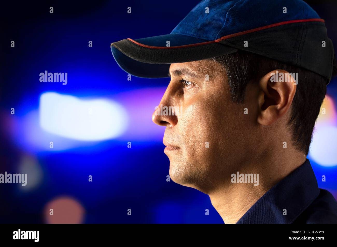 Cropped portrait of a policeman standing alone and staring into a control at night Stock Photo