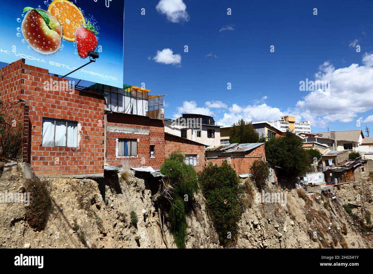 Brick houses on the edge of an unstable earth cliff / ravine in the central Miraflores district overlooking Avenida del Poeta, La Paz, Bolivia. Many of La Paz's hillside neighbourhoods have been built in unstable areas and without proper permits or building controls. Subsidence and landslides causing houses to collapse are common, especially in the rainy season. Stock Photo