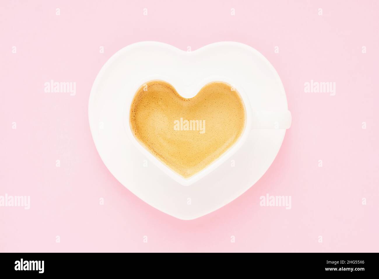 Coffee in heart shape mug on a light pink background. Valentine's day concept. Top view, copy space for text. Stock Photo