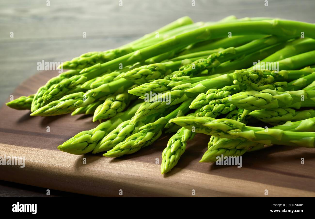 Bunch of fresh green asparagus on a cutting board. Studio closeup representing healthy eating and kitchen activities Stock Photo
